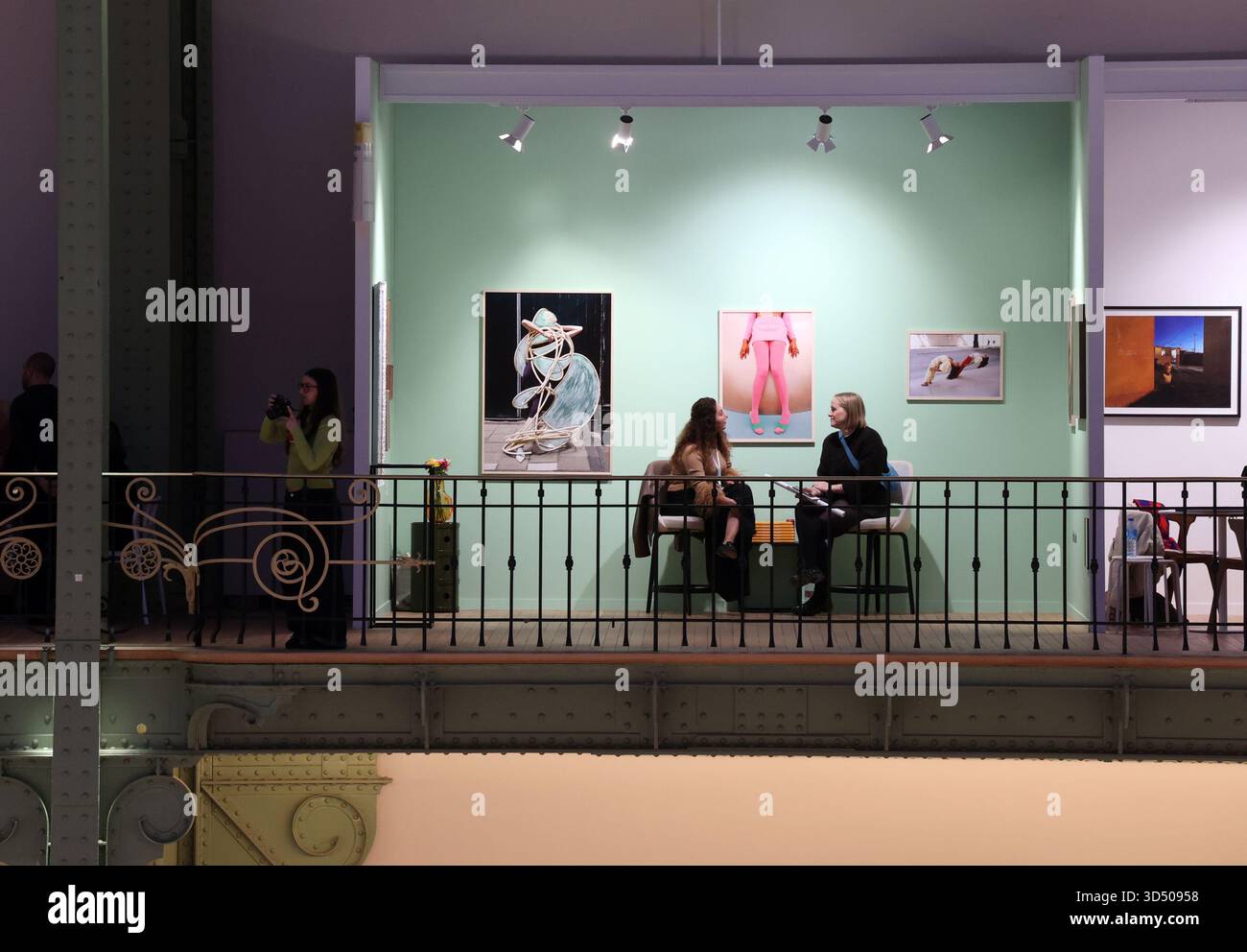 Paris, France. 16th Mar, 2030. A visitor (R) to the Hama Gallery seats ...