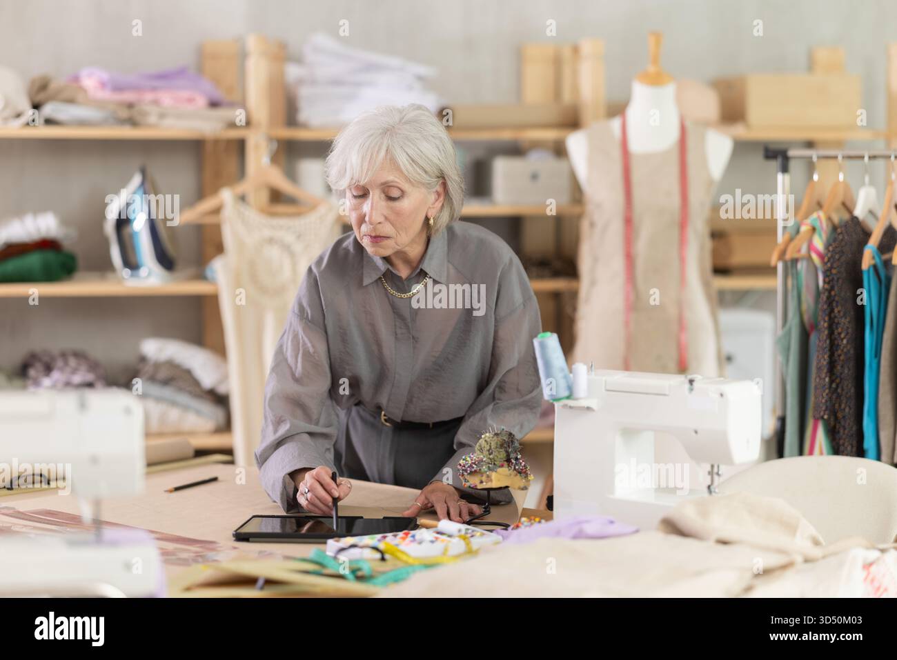Woman dressmaker makes pattern using tablet Stock Photo