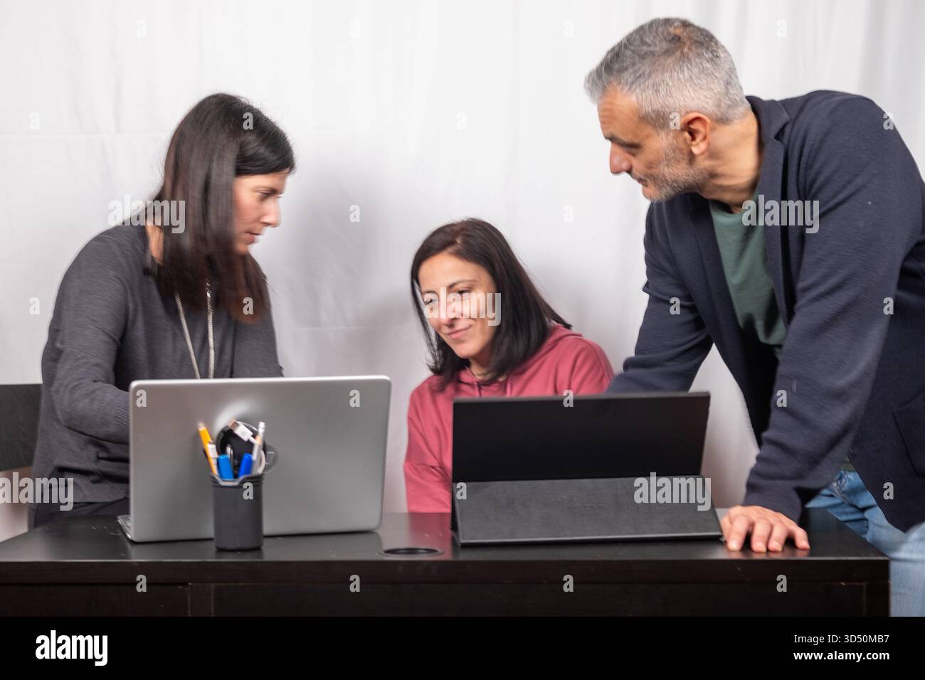 Brainstorming between three colleagues. The two women and the man are about forty years old and are of Italian origin Stock Photo