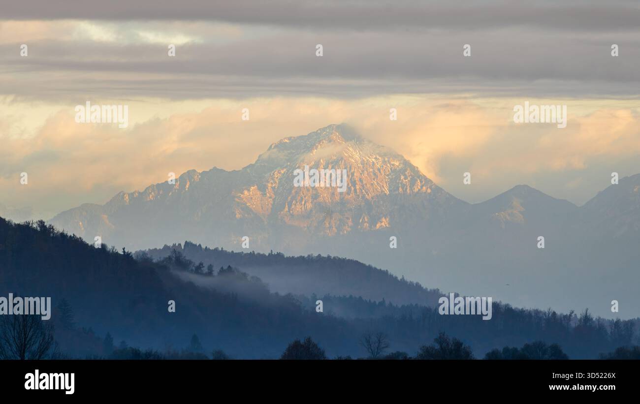 mountain peak with snow and mist under dramatic clouds Stock Photo
