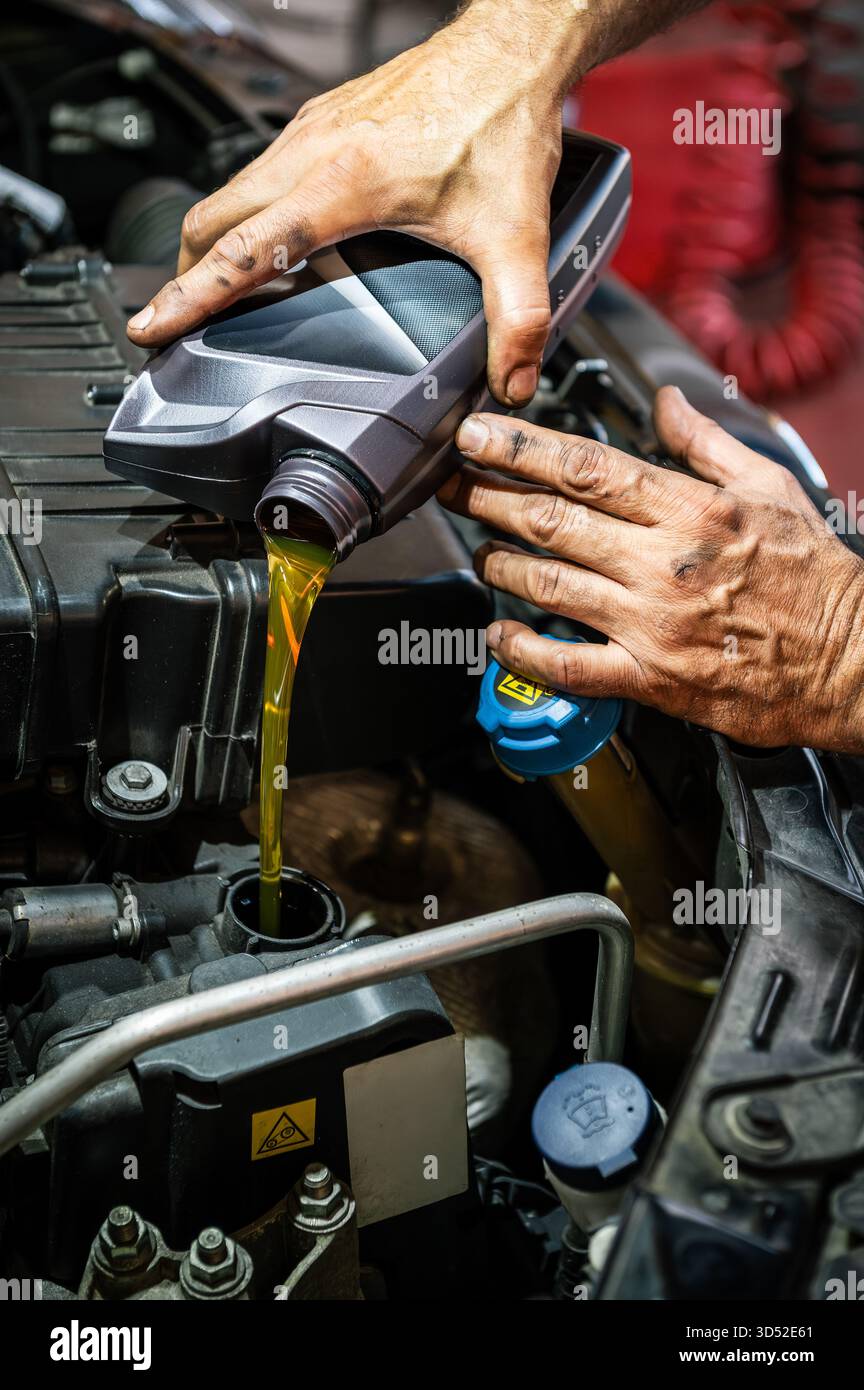 Mechanic hands pouring fresh motor oil into a car engine for maintenance Stock Photo