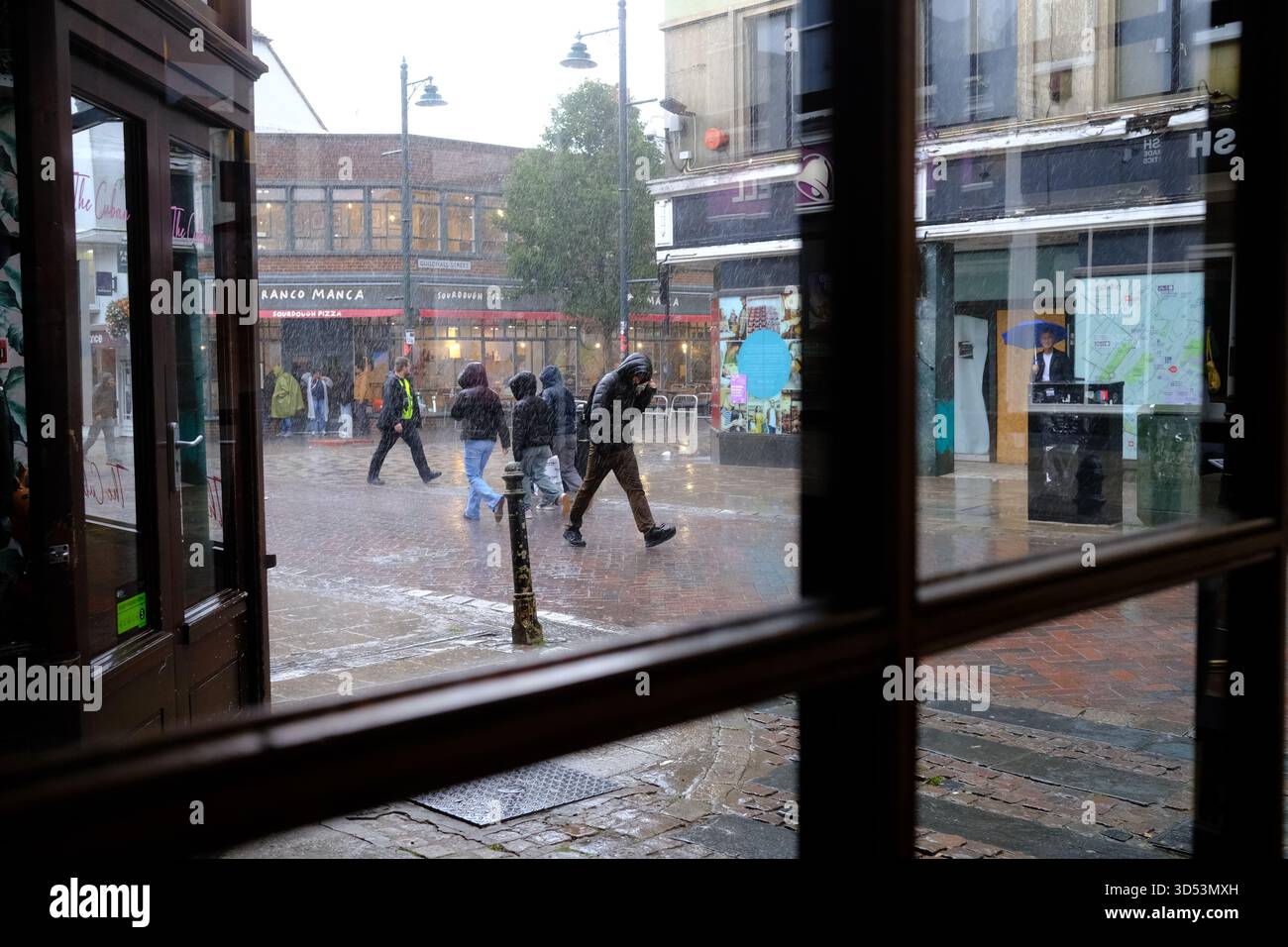 People make a run for cover from  the  torrential rains in Canterbury Kent 13/11/2025 Stock Photo
