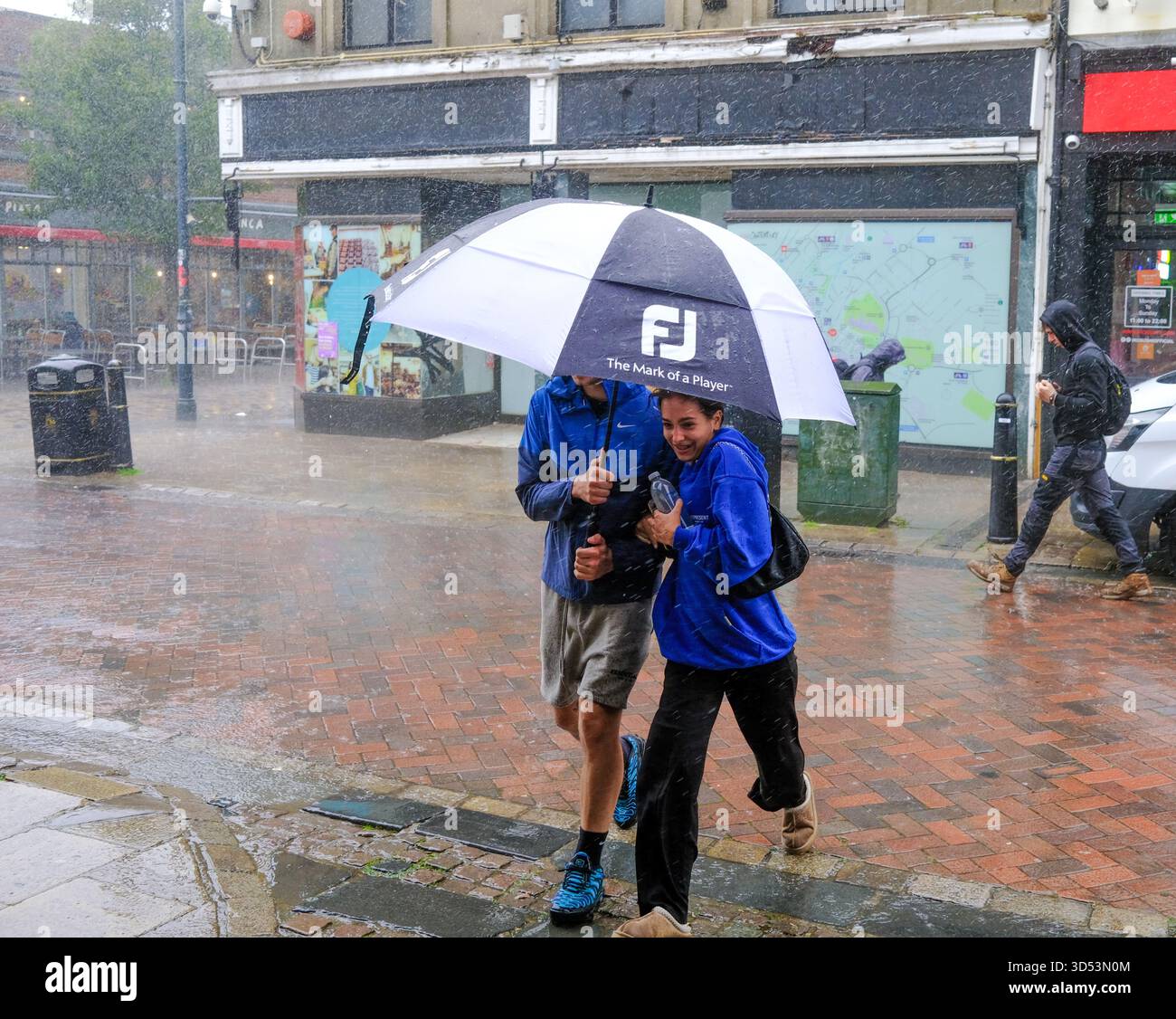 A  couple shelter under an umbrella during torrential rains in Canterbury Kent Canterbury 13/11/2025 Stock Photo