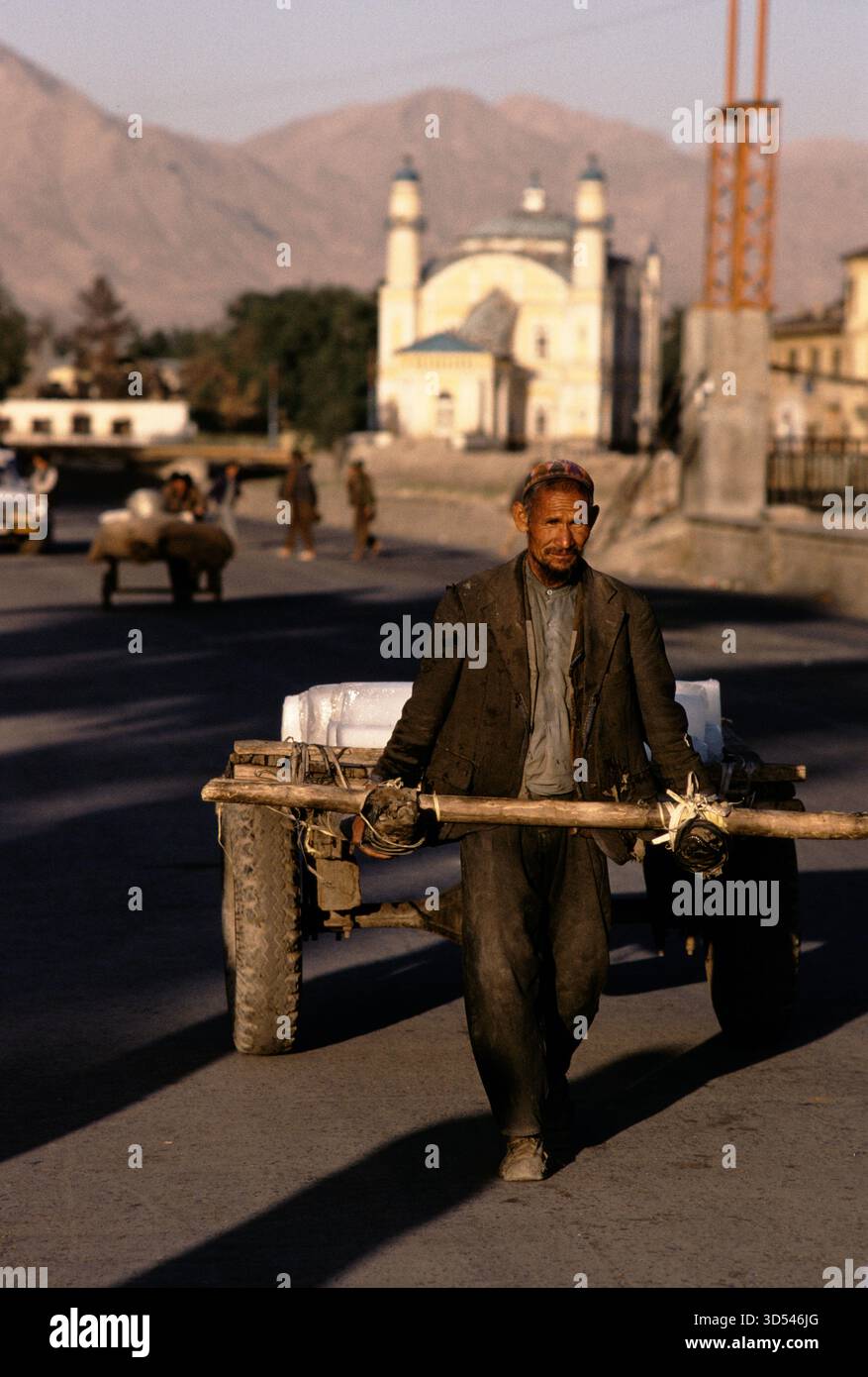 Street scene beside the Kabul River in 1992, showing a man pulling a cart along the road in Kabul, Afghanistan. Stock Photo