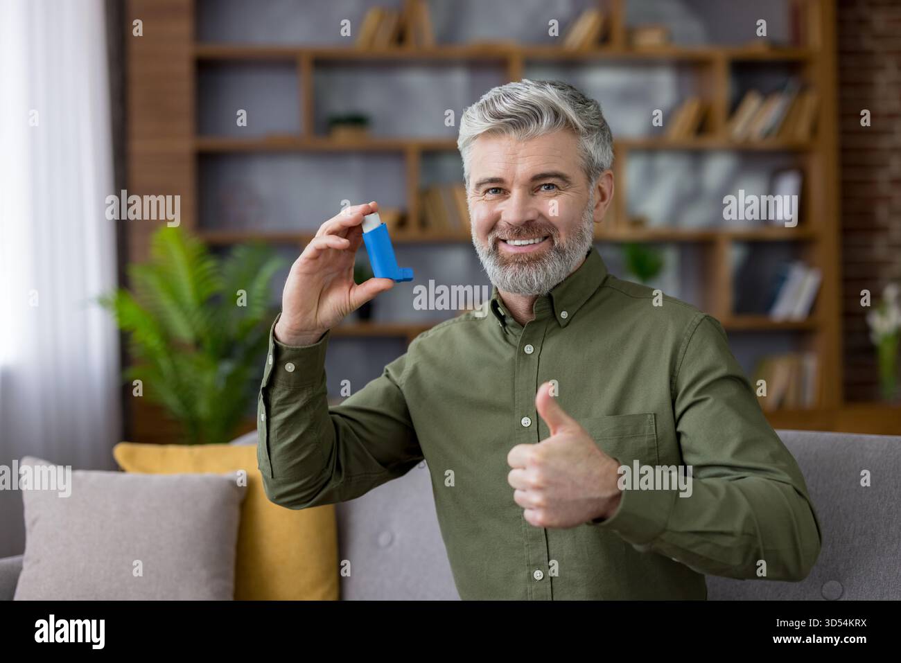 Senior grey-haired man sitting on a sofa in a modern living room ...