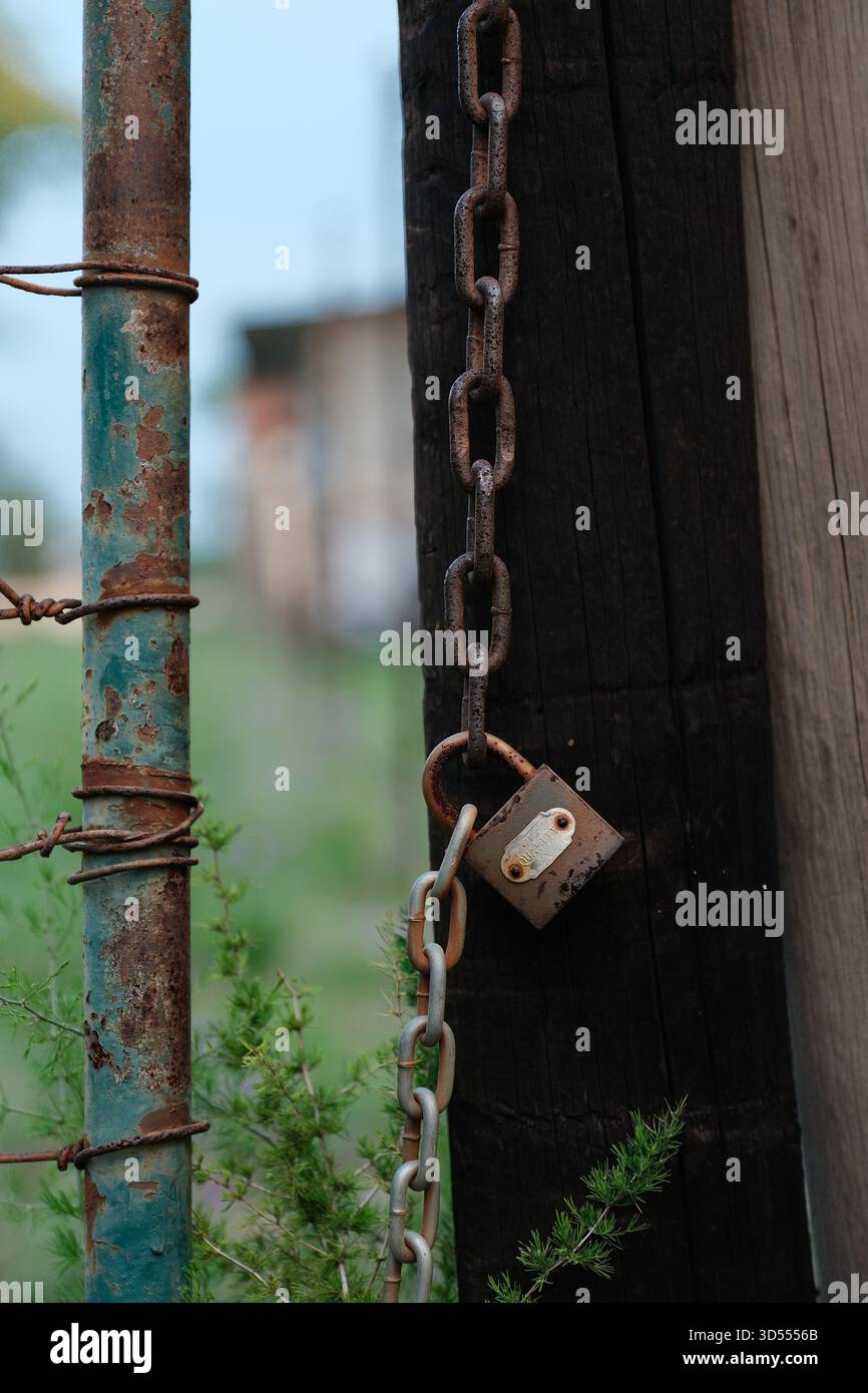 Rusty Padlock and Chain on Weathered Gate Post Outdoors Stock Photo
