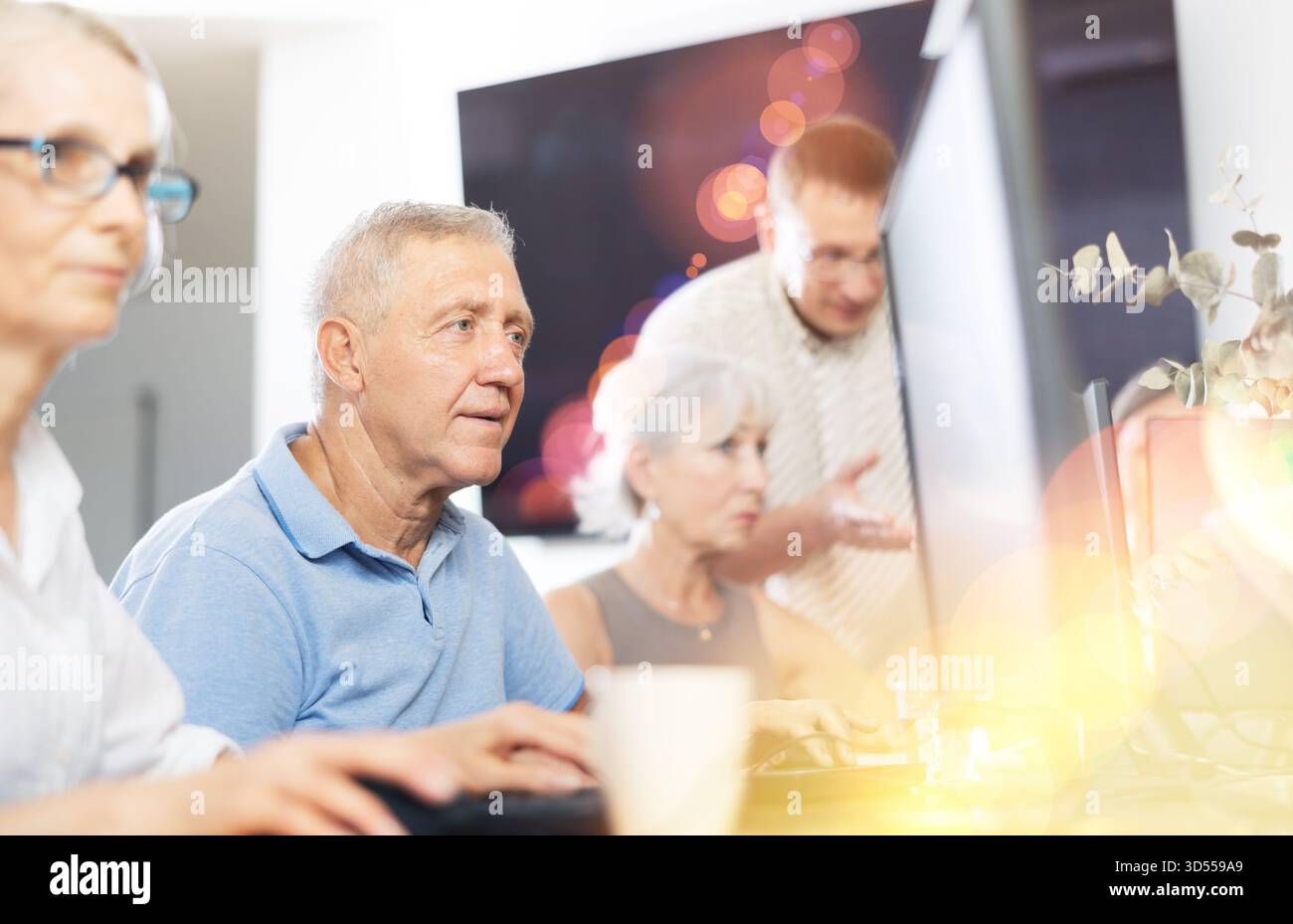 Concentrated elderly man immersed in using computer in library Stock Photo