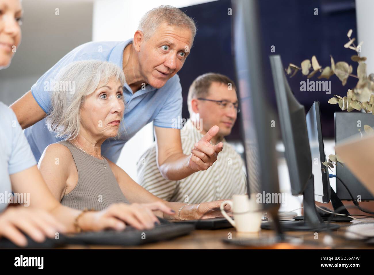 Older mentor explaining something to elderly woman during computer class Stock Photo