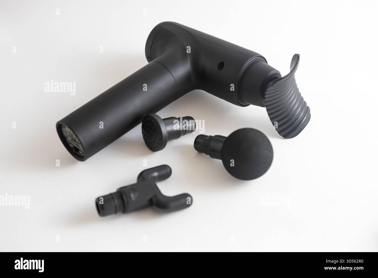 joint and muscle black powered massage gun with various massage tools on a white background Stock Photo