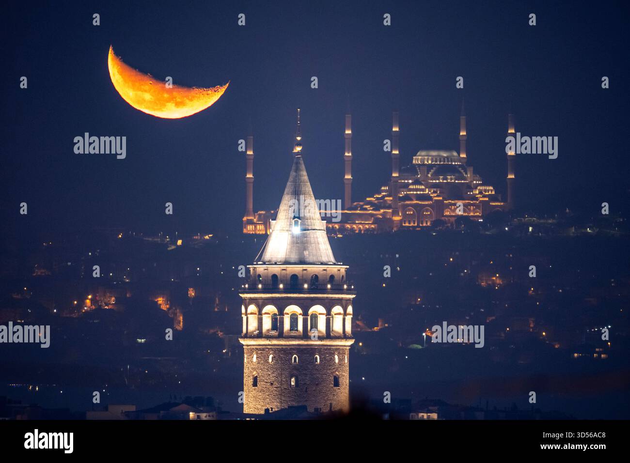 The crescent moon rises behind the Camlica mosque and Galata tower, in ...