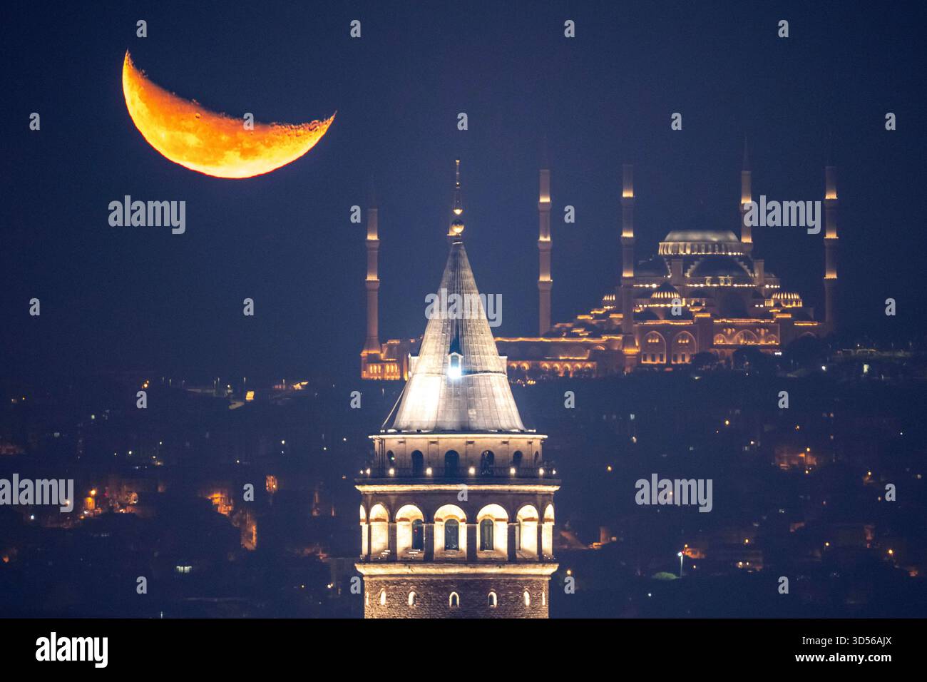 The crescent moon rises behind the Camlica mosque and Galata tower, in ...