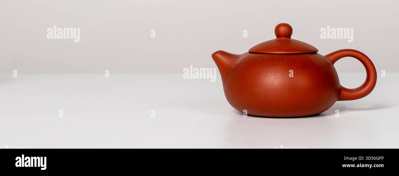 Chinese teapot. Red clay ceramic pot with lid and handle, traditional Asian design for serving hot tea, elegant vintage kitchenware, miniature breakfa Stock Photo
