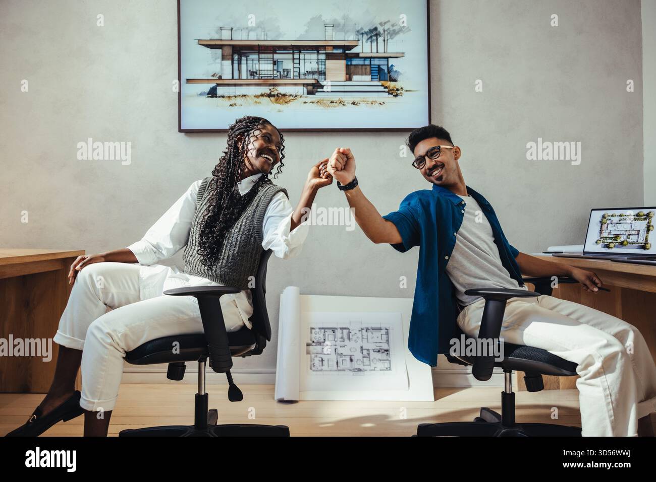 Young male and female professionals collaborating in a modern architecture studio, celebrating design success. Stock Photo