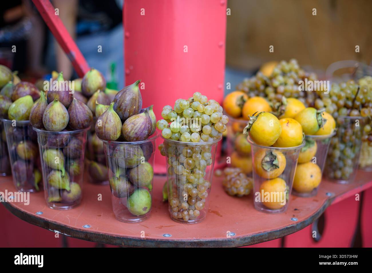 Assorted fruits in plastic cups on a red table. Stock Photo