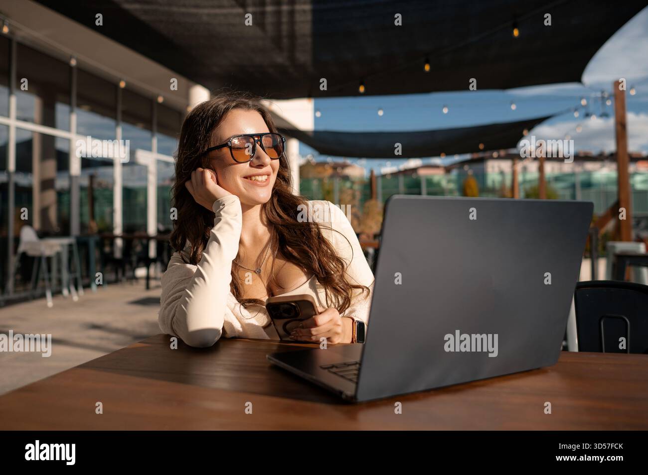 Woman using smartphone and laptop outdoors Stock Photo