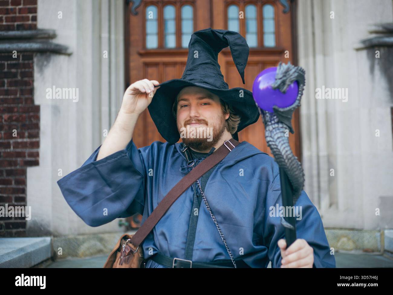 A guy in a wizard costume and a pointed hat with a purple orb Stock Photo