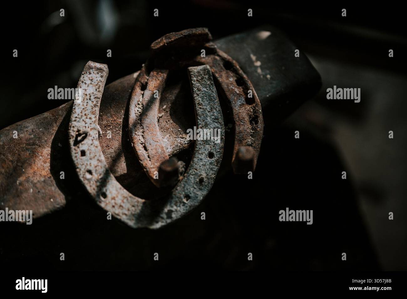 Rusty horseshoes resting on a blacksmith's anvil Stock Photo