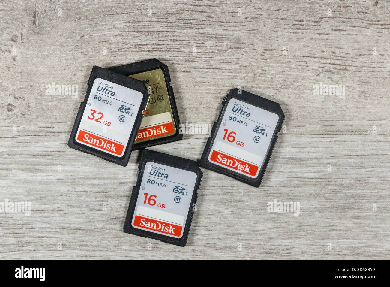 Top view of several SanDisk Ultra SD memory cards of different capacities on a wooden surface Stock Photo