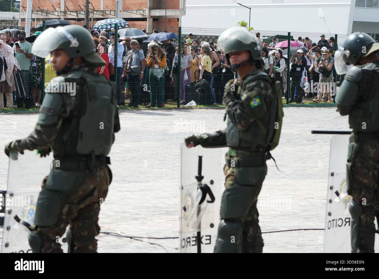 Attendees line up outside a fence to get into the venue for the COP30 U ...