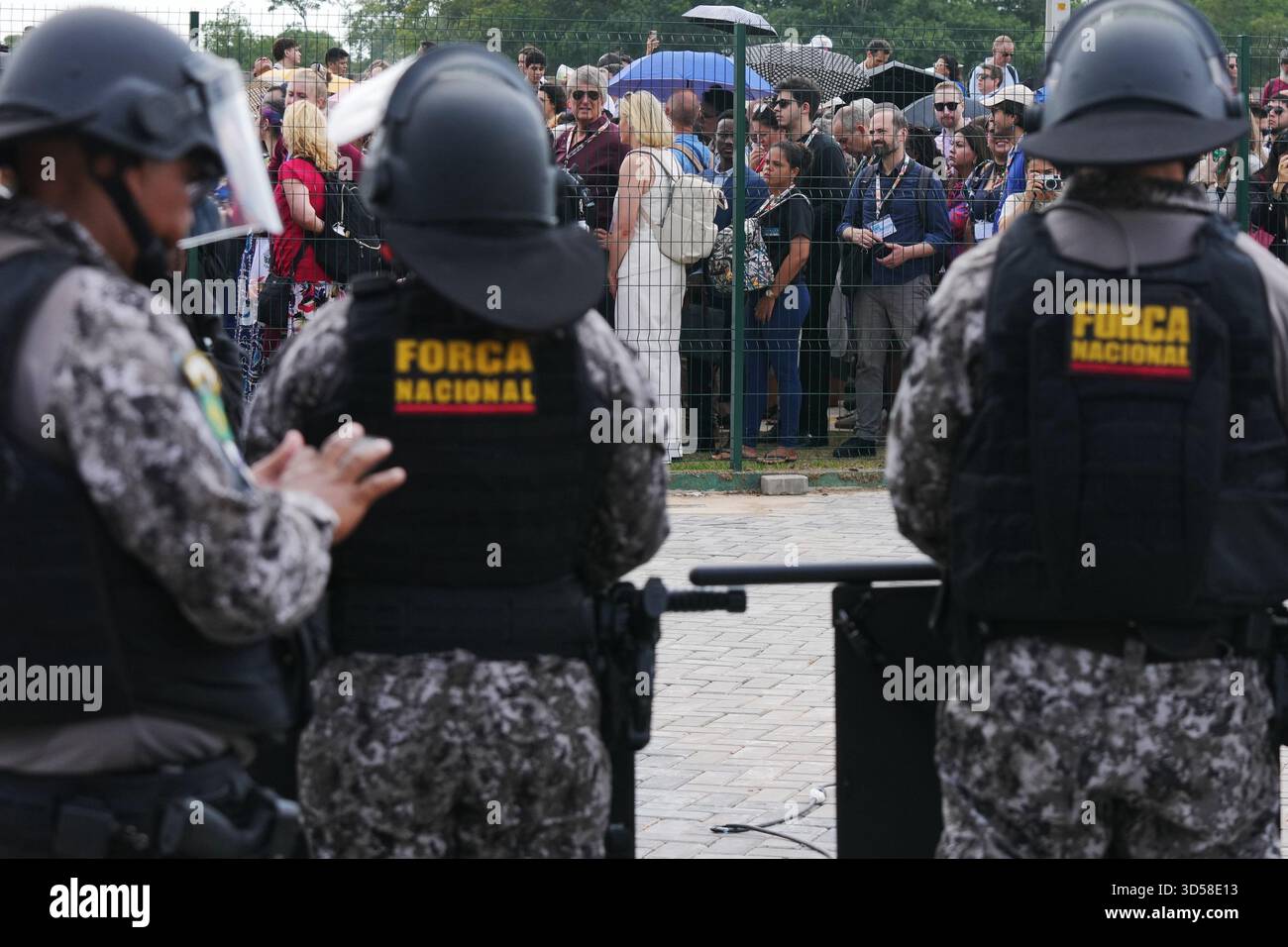 Attendees line up outside a fence to get into the venue for the COP30 U ...