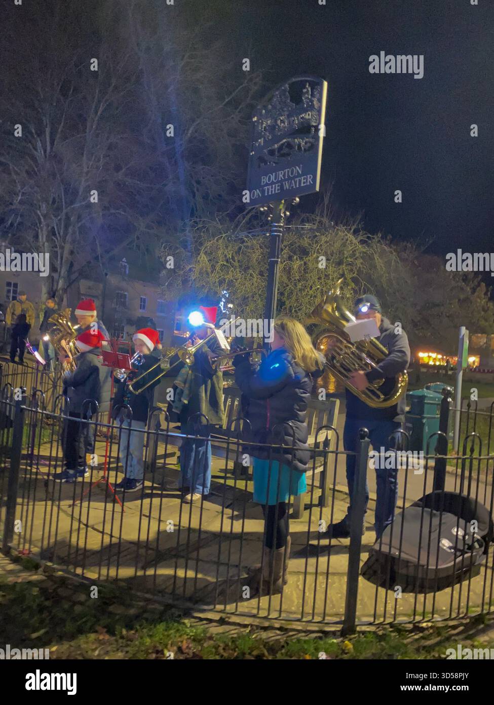A village community band playing Christmas carol tunes in Bouton-on-the-Water, nicknamed ‘Venice of the Cotswolds’ because of its nearby charming low - Smartphone Captured Stock Image