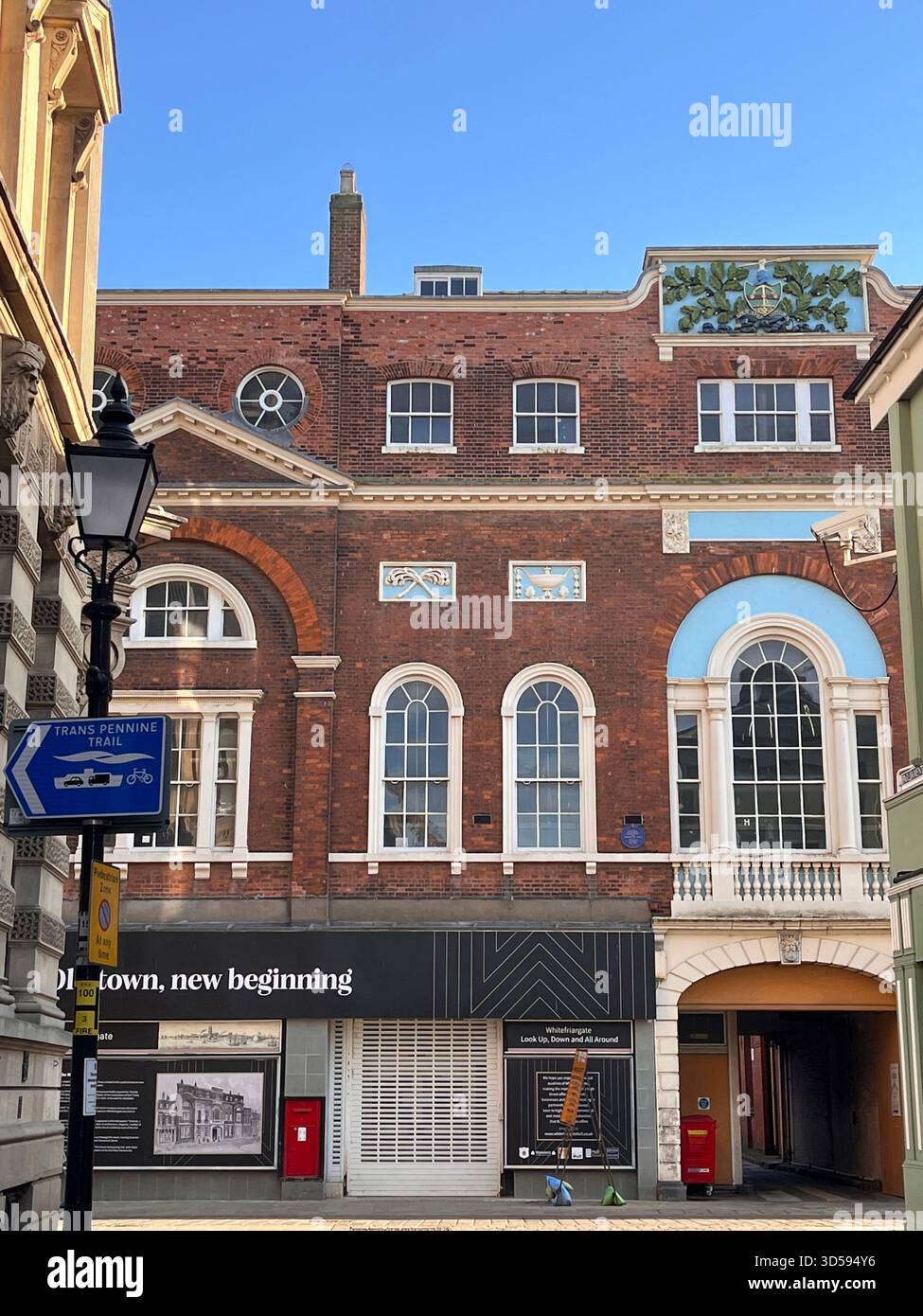 A Georgian-style red-brick commercial building in Hull, England, featuring large arched windows and elegant classical proportions. The sunny lighting - Smartphone Captured Stock Image