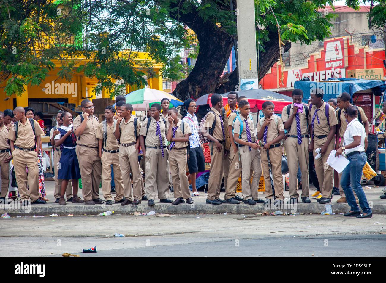 Jamaica, Kingston. male students waiting for the bus to bring them home. Stock Photo