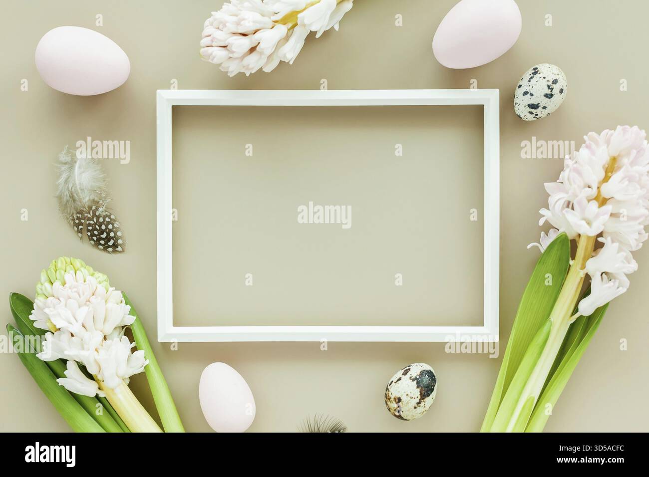 Subtle Easter mockup with white frame, easter eggs and flowers on a pastel colored background Stock Photo
