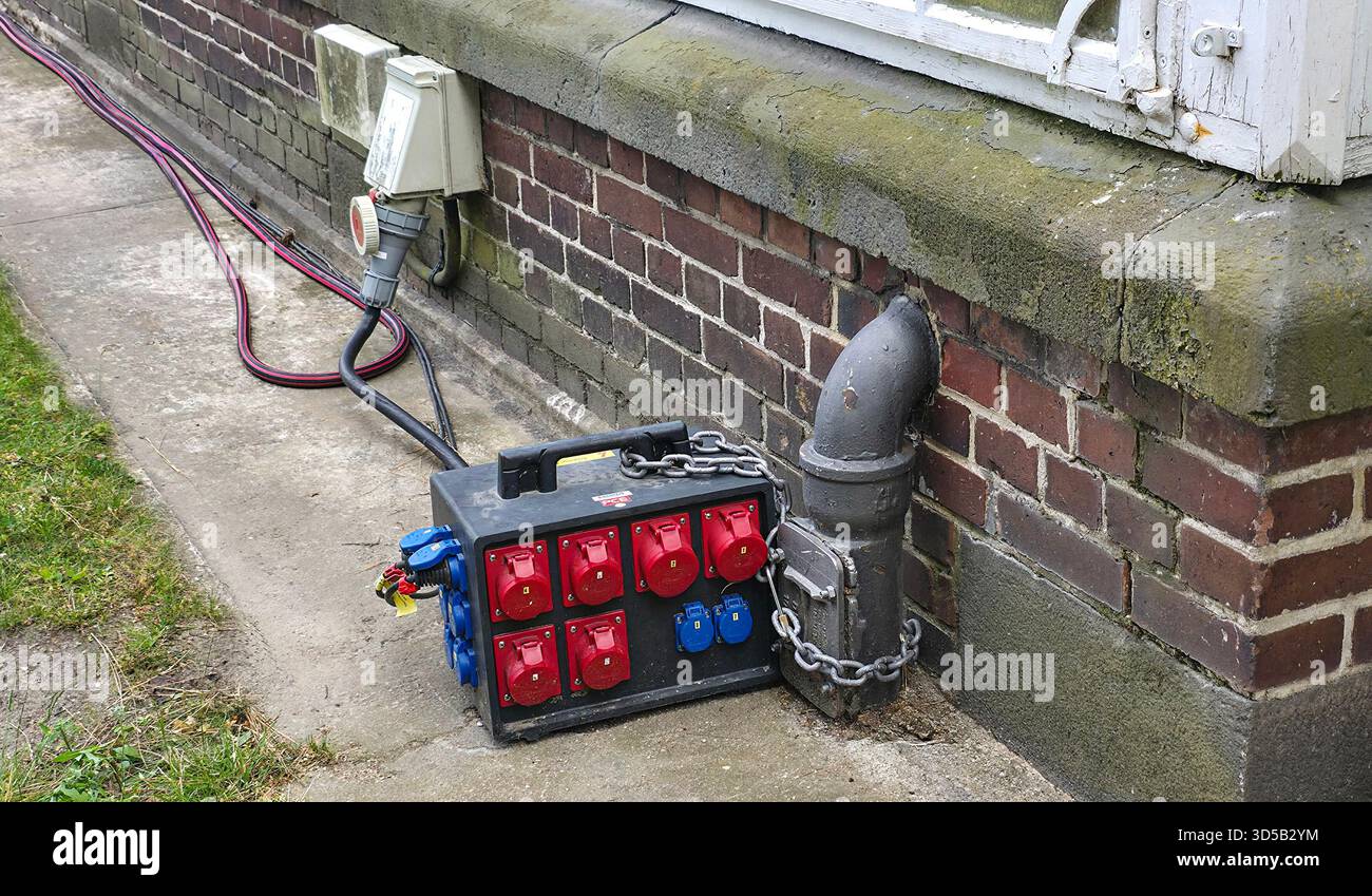 Berlin, Germany - July 03, 2025: . Electrical power distribution box features multiple outlets beside brick wall - Smartphone Captured Stock Image