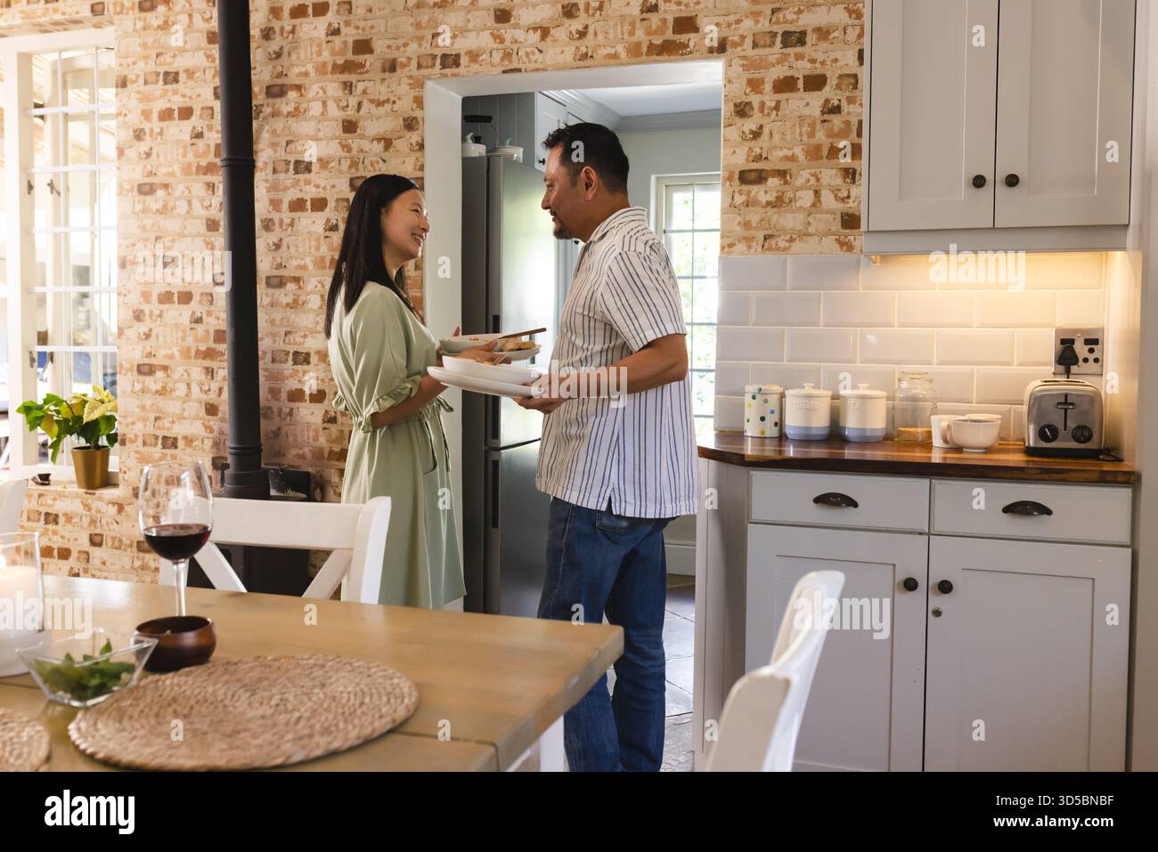 Asian couple in kitchen sharing laugh while preparing dinner together Stock Photo
