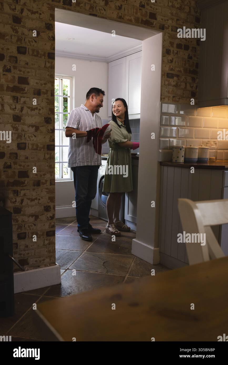 Asian couple cooking together in cozy kitchen, sharing joyful moment Stock Photo