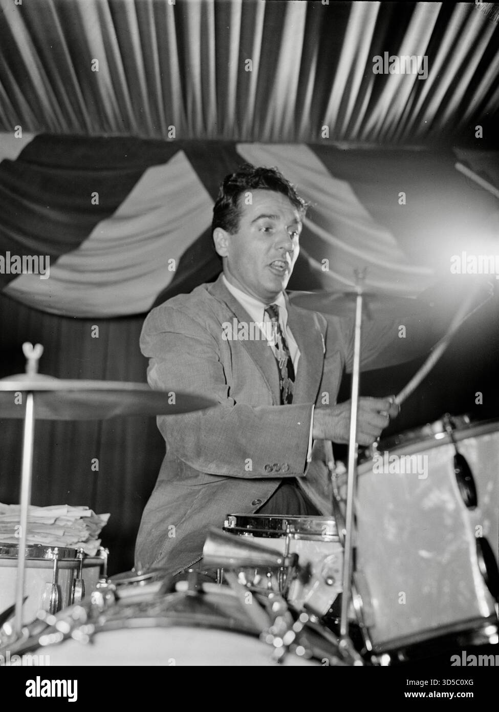 William P. Gottlieb - Gene Krupa during a performance. He is widely regarded as one of the most influential drummers in the history of popular music. Krupa brought a show-stopping visual drama to his performances, using a high arm action that emphasized his hand movements. His drum solo on Benny Goodman's 1937 recording of "Sing, Sing, Sing" elevated the role of the drummer from that of an accompanist to that of an important solo voice in the band. Krupa also appeared as a movie star in films like the original Some Like It Hot and Ball of Fire. Stock Photo