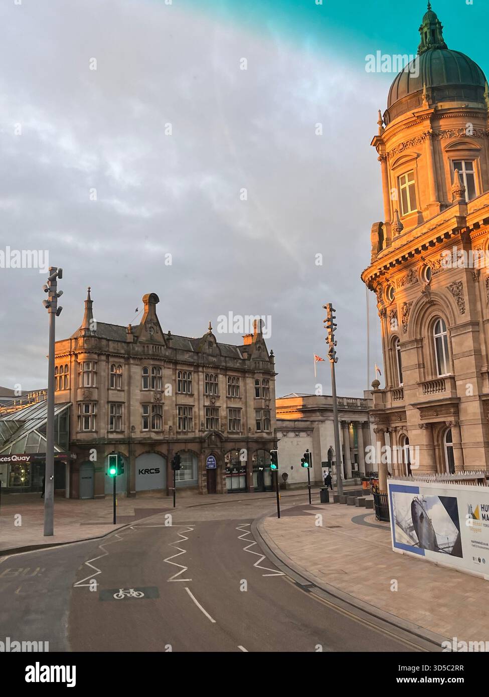 Empty urban street surrounded by historic buildings under soft golden hour light in Hull, England. Calm atmosphere and dramatic sky over traditional - Smartphone Captured Stock Image