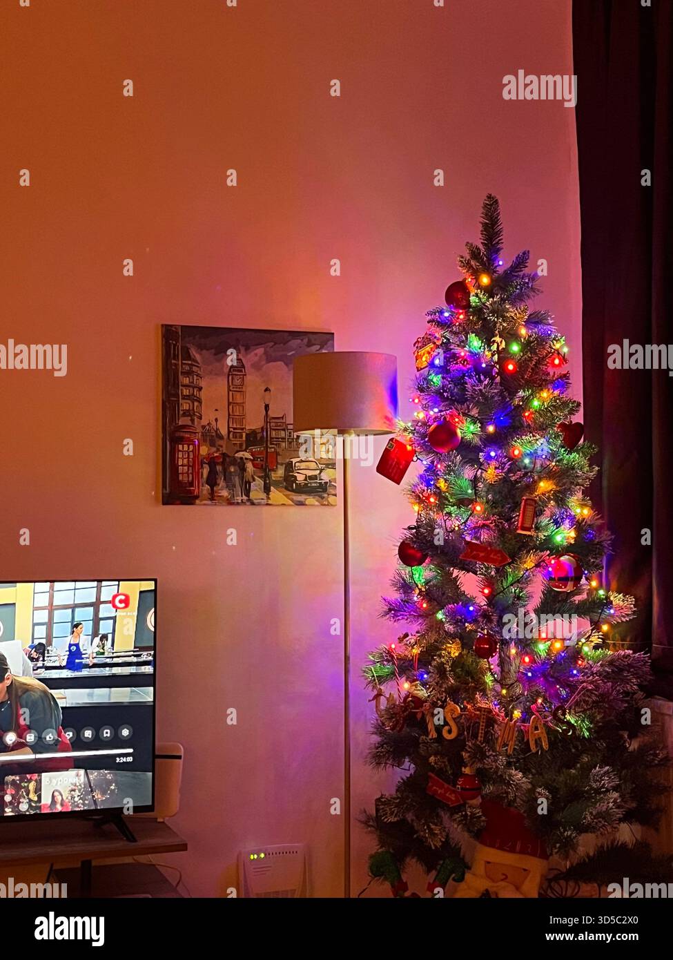 Cozy interior scene of a living room decorated with a colourful Christmas tree and warm ambient lighting in Hull, England. Festive home atmosphere - Smartphone Captured Stock Image