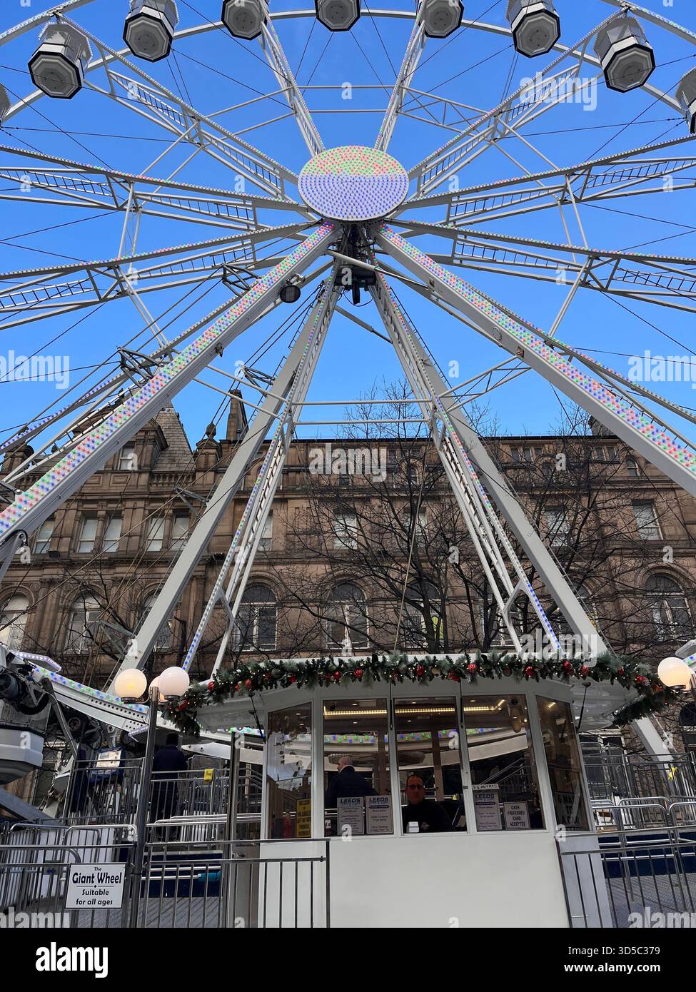 Modern Ferris wheel dominating a city square against a blue sky in Hull, England. Popular seasonal attraction and urban landmark. Large Ferris Wheel . - Smartphone Captured Stock Image