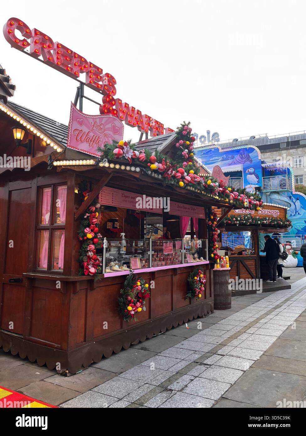 Traditional wooden Christmas market stall decorated with garlands and festive ornaments in Leeds city centre, England. Seasonal street market atmosphe - Smartphone Captured Stock Image