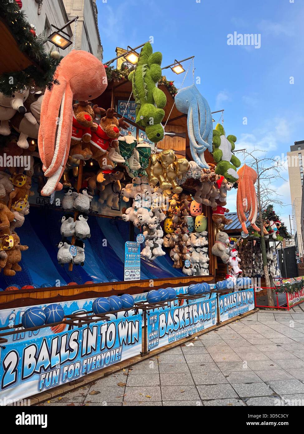 Traditional fairground game booth with hanging plush animals and prizes at a Christmas market in Leeds, England. Colorful outdoor winter entertainmen - Smartphone Captured Stock Image