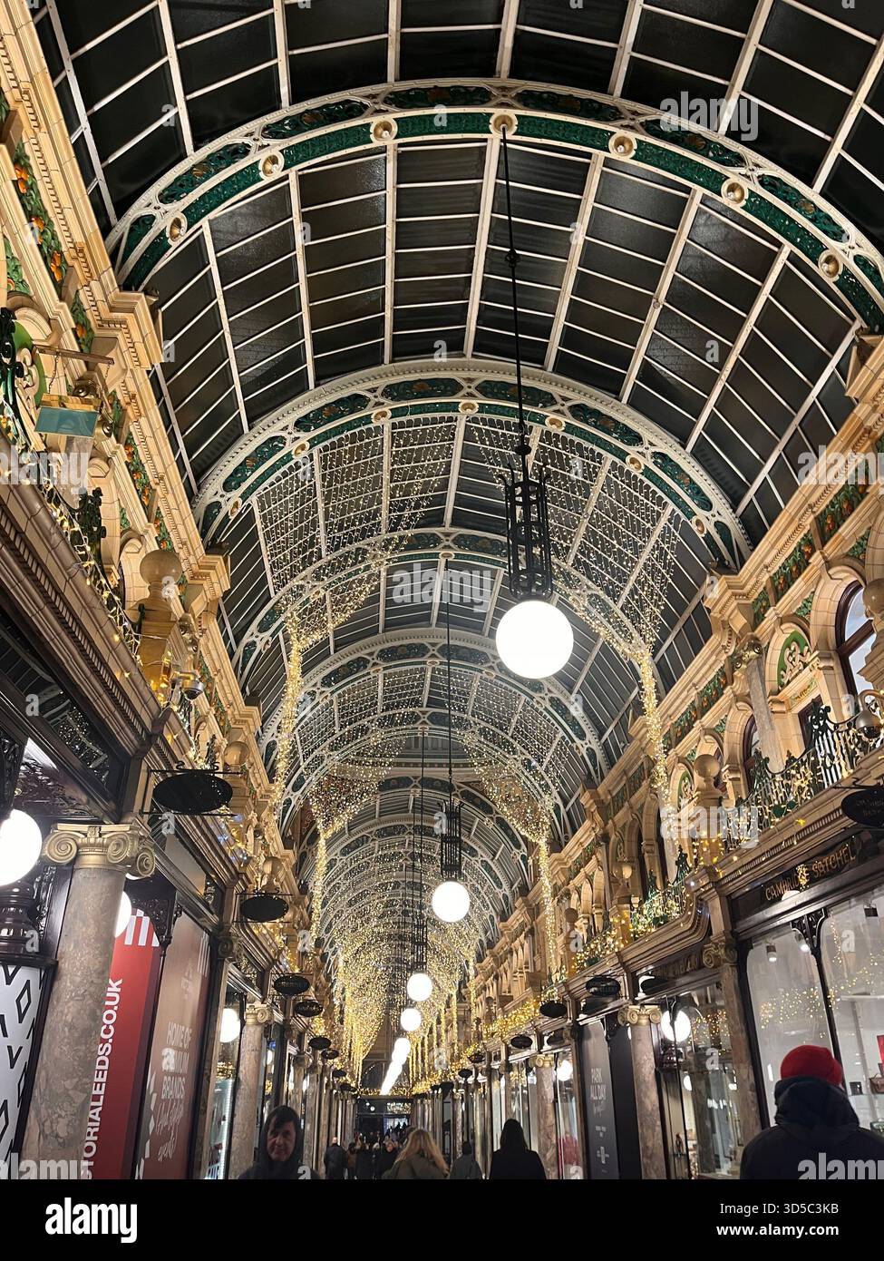 Interior view of an ornate Victorian covered shopping arcade with arched glass ceiling and decorative ironwork in Leeds, England. - Smartphone Captured Stock Image