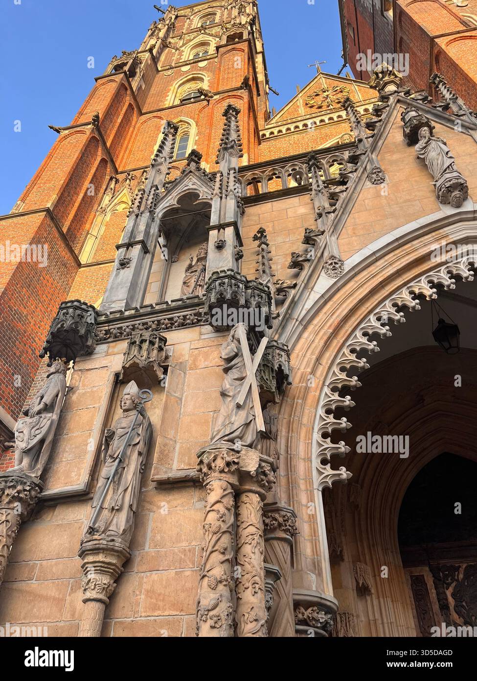 Close-up view of the ornate Gothic entrance of a cathedral in Wrocław, Poland, featuring detailed stone carvings, statues - Smartphone Captured Stock Image