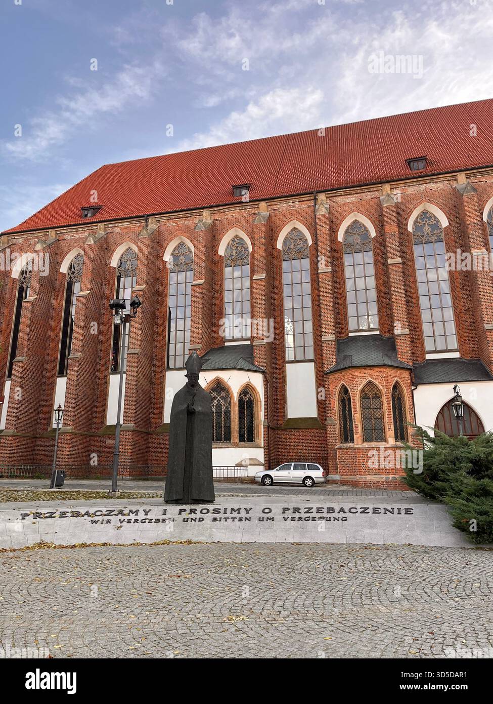 A side perspective of a large Gothic brick church in Wrocław, Poland, with tall narrow windows and traditional architectural patterns. - Smartphone Captured Stock Image