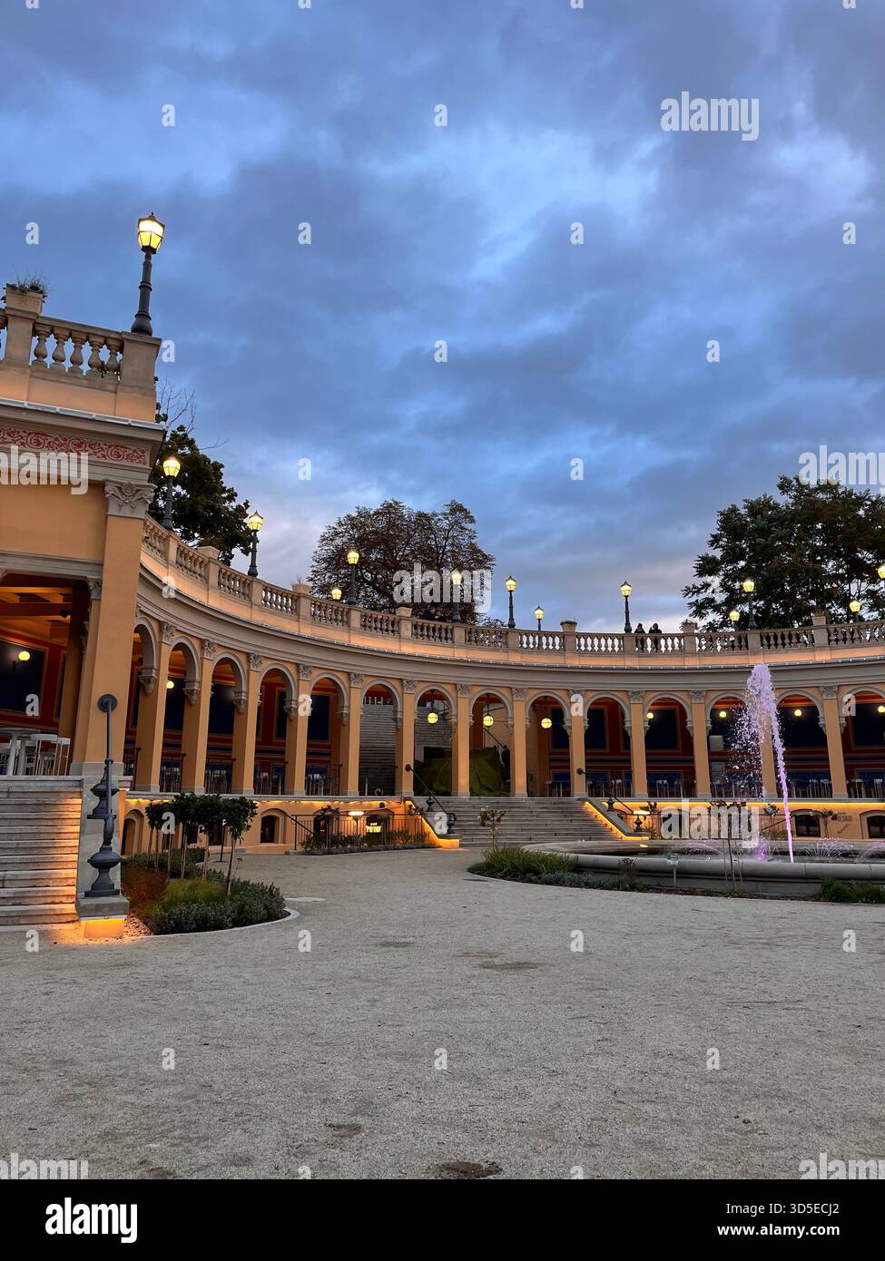 A wide view of a curved colonnade in Wrocław, Poland, illuminated by warm lights with a dramatic evening sky above. - Smartphone Captured Stock Image