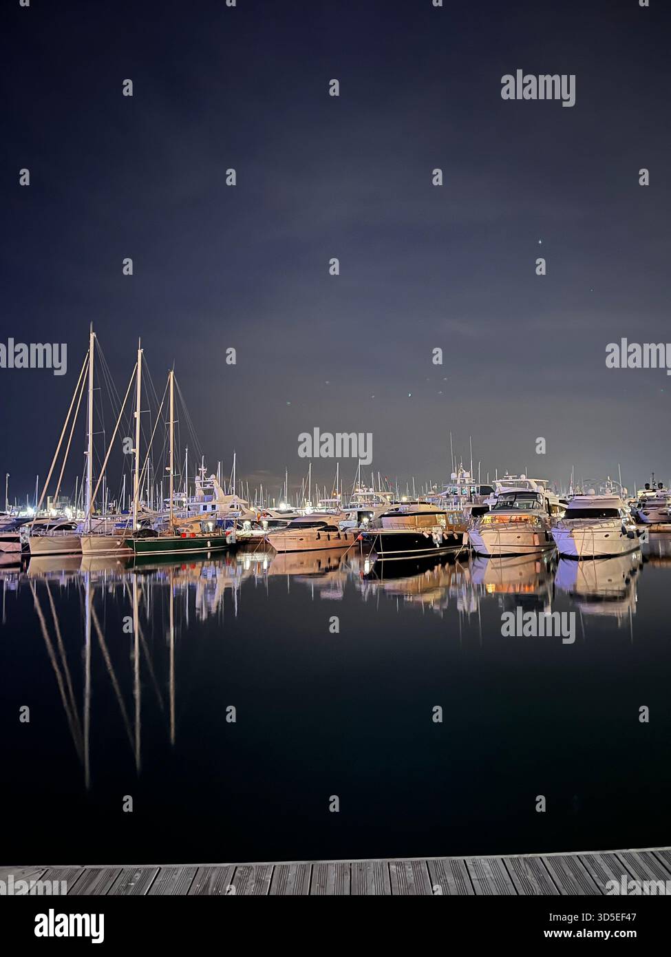 A beautiful nighttime scene featuring luxury yachts docked in the Alicante marina. - Smartphone Captured Stock Image