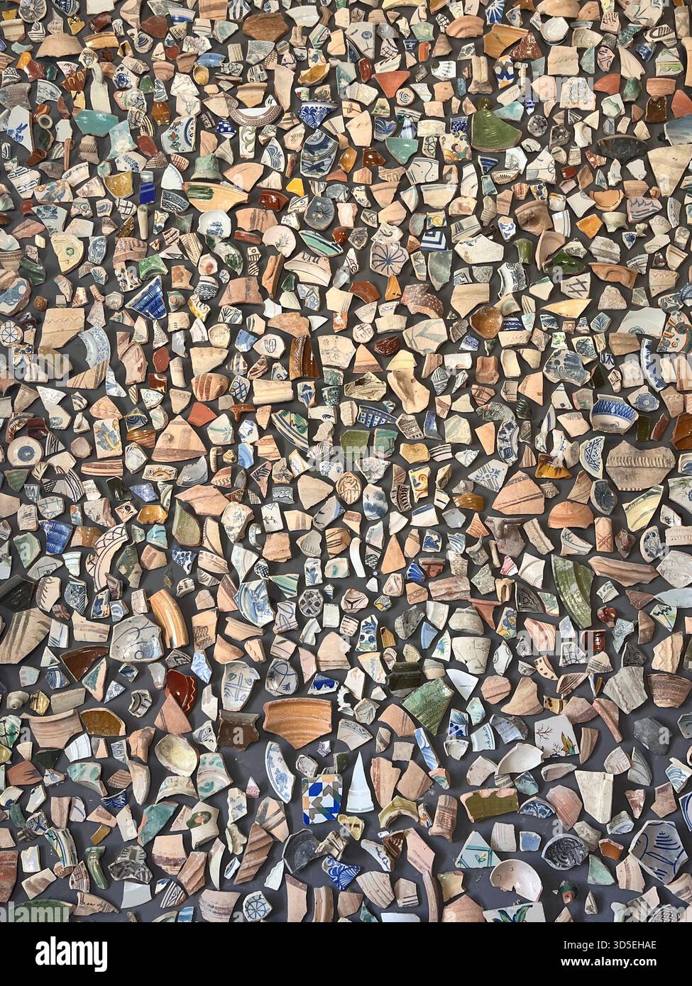 Second close-up of a vibrant mosaic wall composed of diverse broken ceramic pieces in Alicante, Spain. Rich textures and patterns form a striking hand - Smartphone Captured Stock Image