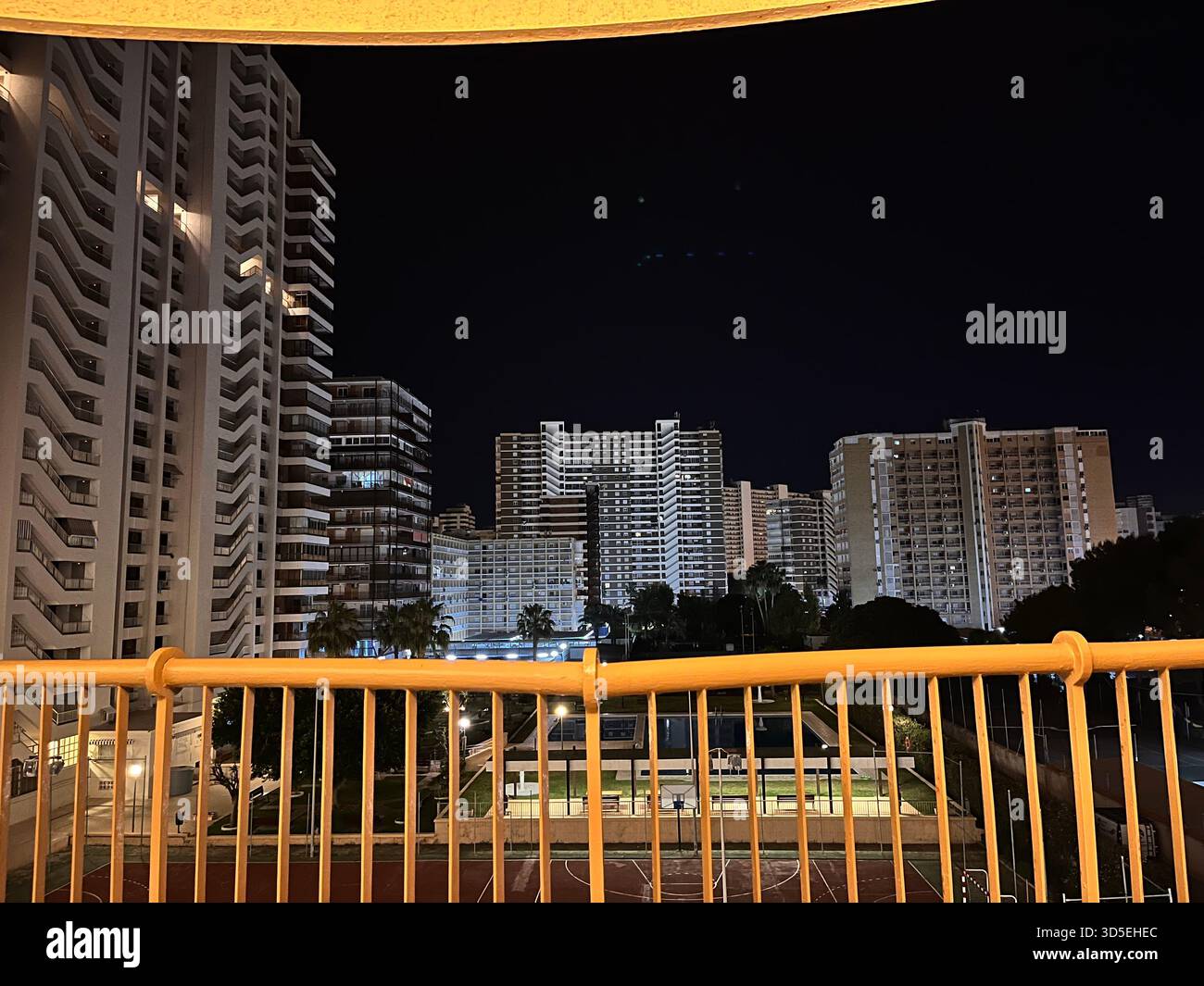 A nighttime urban scene with illuminated modern residential towers and a dark sky above. Captured in Alicante, Spain, - Smartphone Captured Stock Image