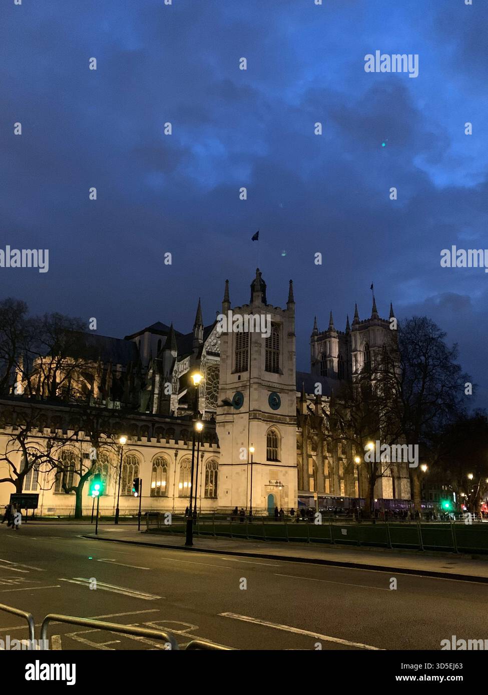 A historic architectural building photographed at dusk with illuminated windows and a deep blue sky. Street lights - Smartphone Captured Stock Image
