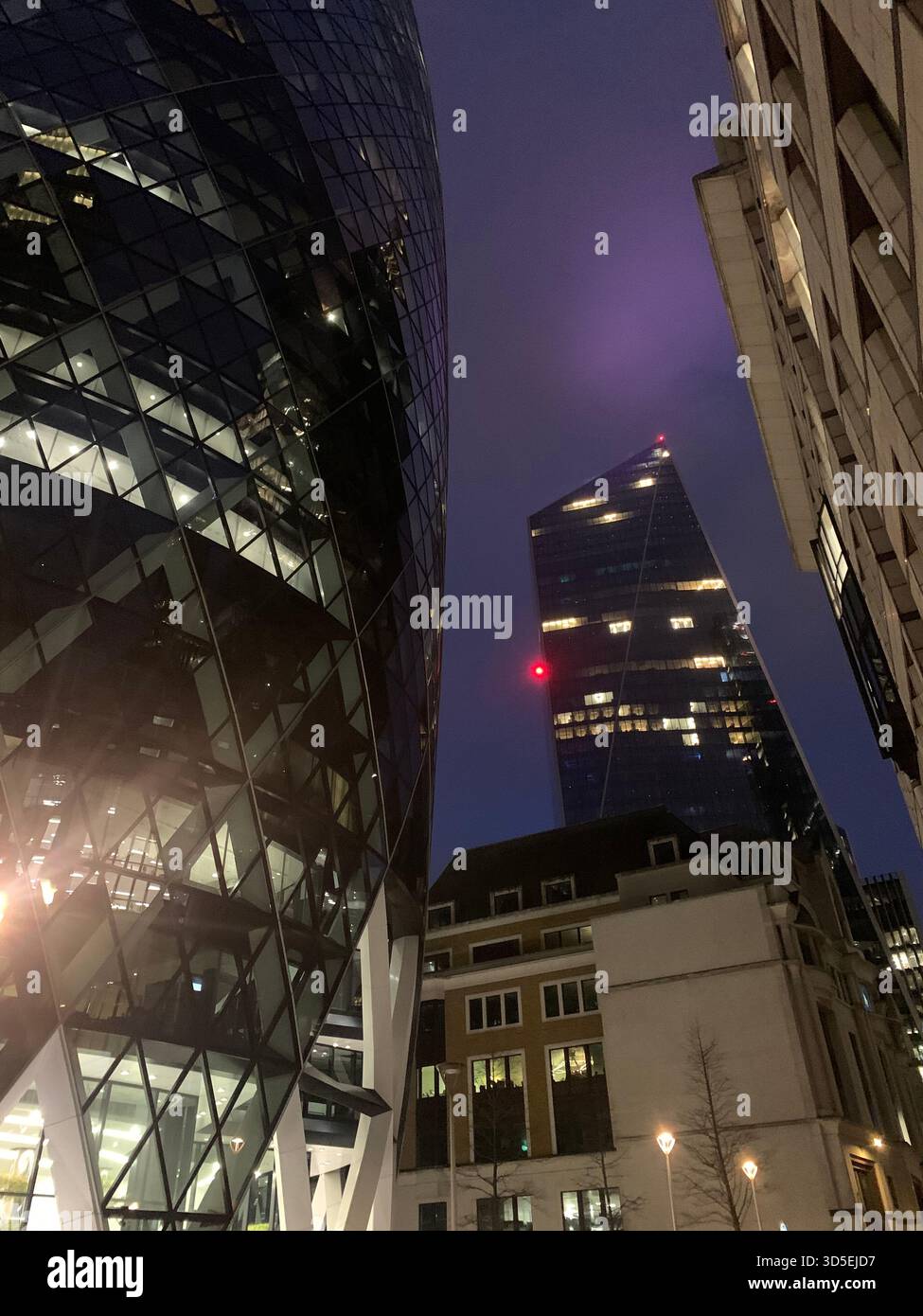 A dramatic nighttime cityscape featuring the Gherkin and surrounding modern skyscrapers in the City of London. - Smartphone Captured Stock Image