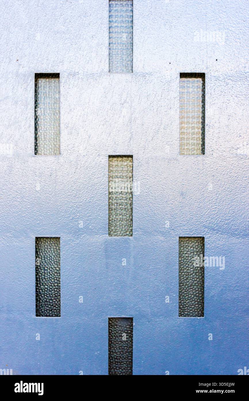 Blue Textured Wall With Vertical Glass Windows Creating Modern Geometric Pattern Stock Photo