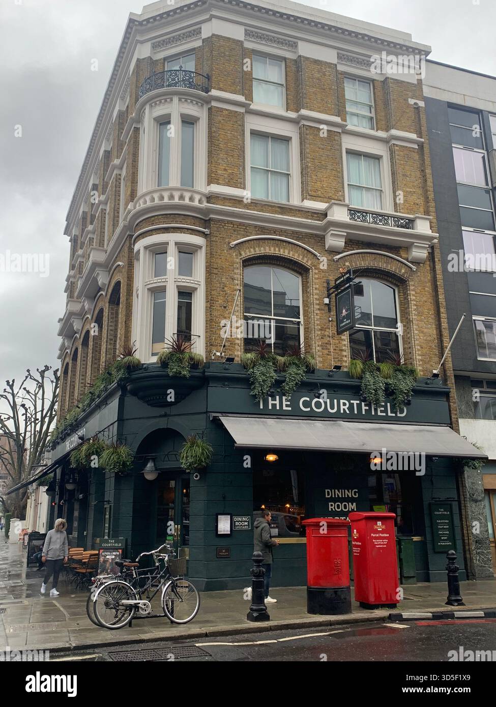 Classic London pub exterior with traditional architecture and red British post boxes. - Smartphone Captured Stock Image