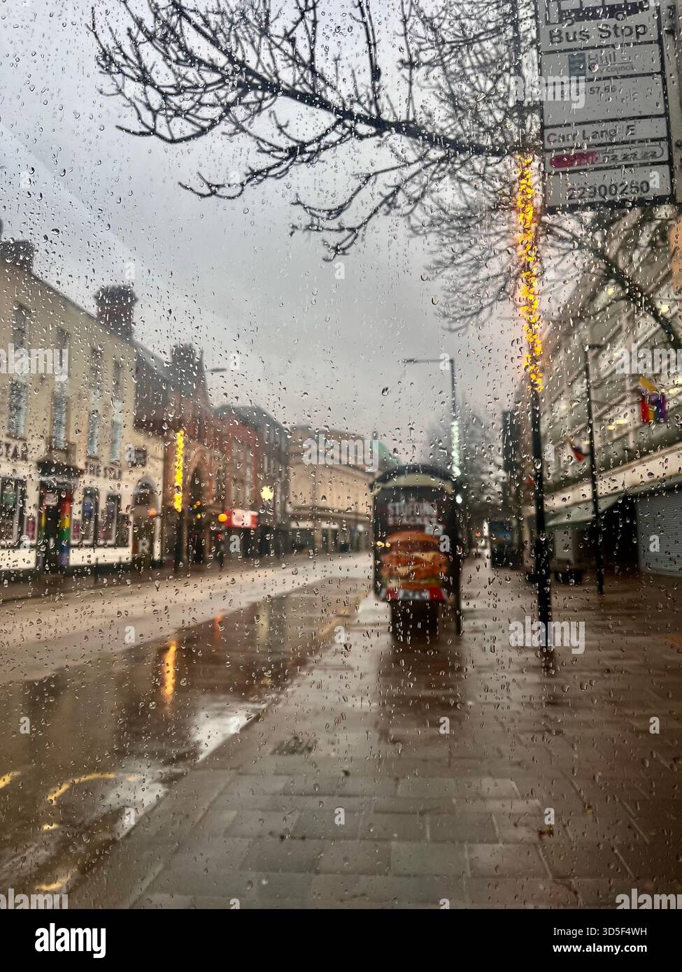 Wet city street in Hull, England, during rainfall with reflections of lights on the pavement. Moody urban atmosphere on a cold, rainy evening. - Smartphone Captured Stock Image