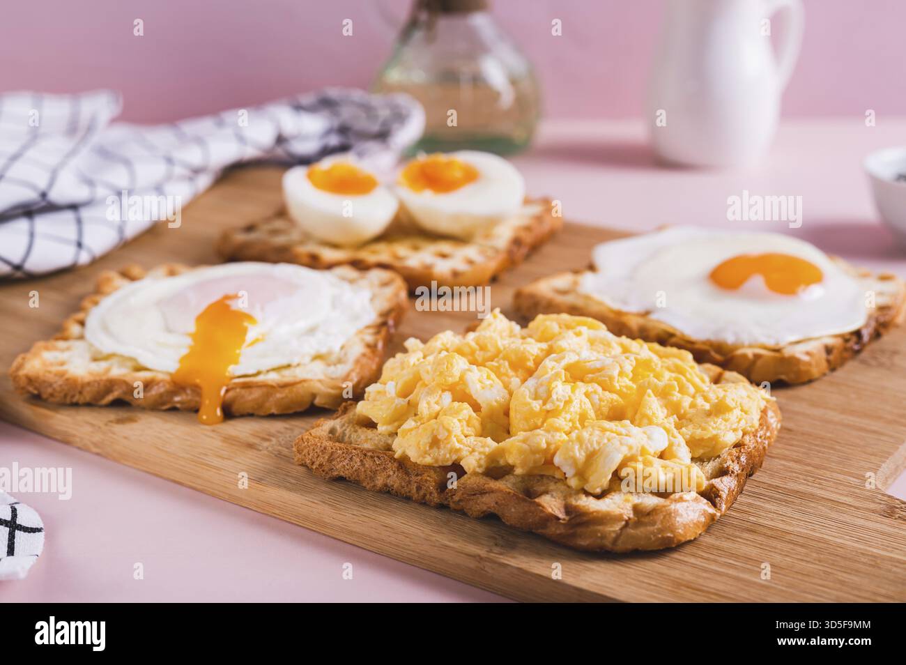 Scrambled egg, poached egg, fried egg, boiled egg on toast on a board Stock Photo